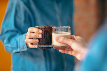 Close up of young couple hands clinking or toasting glasses of coffee talking sharing showing love...