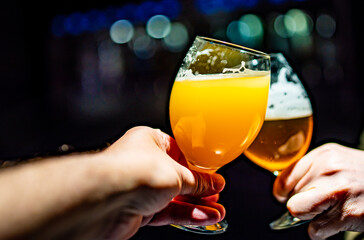 two glass of beer in hand. Beer glasses clinking in bar or pub