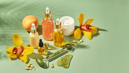 Cosmetic care products in glass bottles with orchid flowers - serums, cream, gel, oils. Concept for...