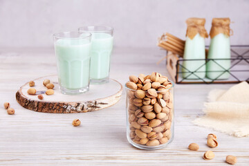 Pistachio milk in glasses and bottles, nuts in jar. Healthy vegetarian and vegan drink, plant based milk substitute. The concept is lactose free, dairy free. 