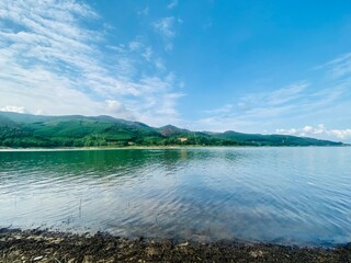 Beautiful natural scenery on a cloudy summer morning with a blue lake and green mountains reflected on the lake surface