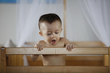 Un bébé tire la langue au bord de son lit