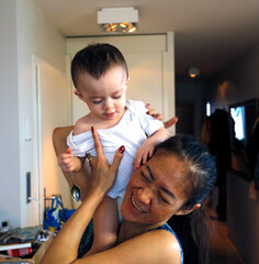 Une très jolie maman asiatique rit avec son bébé sur les épaules