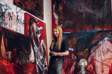 Young redhead woman painter standing by her art masterpiece on a big canvas