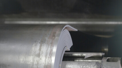 Metal tape is moving on rolling machine close-up. Rolling sheet rolling mill