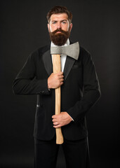 Serious bearded man in suit holding axe dark background