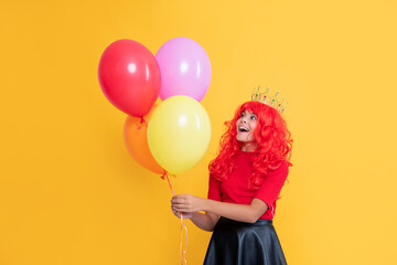 happy child in crown with party balloon on yellow background. wow