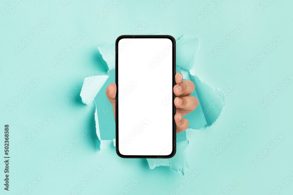 Wall mural person showing white empty smartphone screen breaking through paper