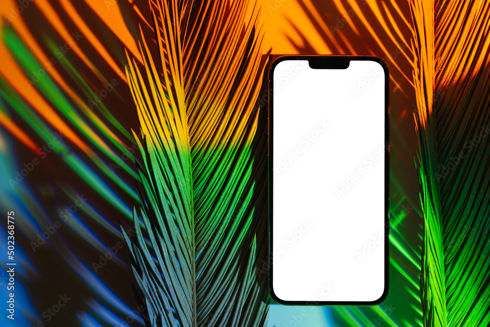 Wall mural mockup smartphone with tropical palm leaf on abstract background in neon gradient. mobile phone ith 