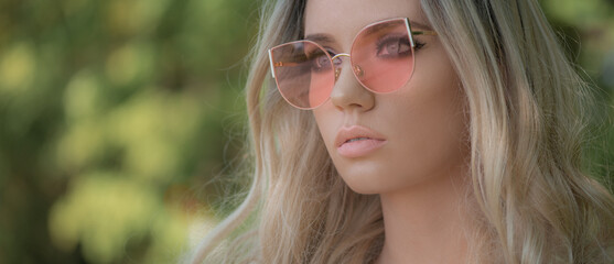 Portrait of beautiful stylish blonde woman in pink sunglasses in outdoor.