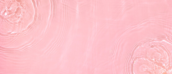 Fototapeta premium Abstract summer banner background Transparent pink clear water surface texture with ripples, splashes. Water waves in sunlight, copy space, top view. Cosmetics moisturizer micellar toner emulsion