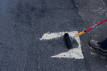 Worker applies one phase of waterproofing with a roller, the first basic layer