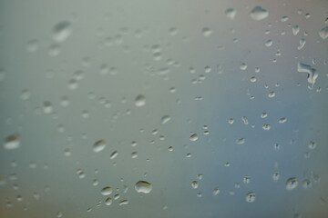 Rain drops on window glasses surface with cloudy background . Natural Pattern of raindrops isolated on cloudy background. Drops of water on glass window over grey background.