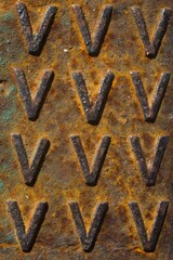 evocative image of rusted surface texture with embossed "V" motifs
