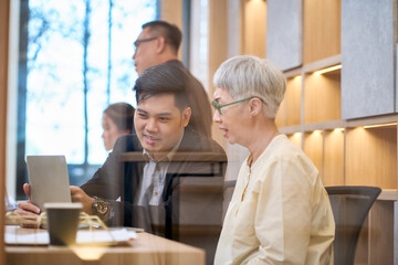 Businessman teach elderly staff woman for start working in office with laptop technology