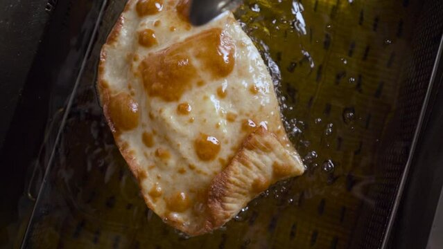 The process of deep-frying chebureks in boiling oil.