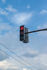 Red light on the semaphore against the cloudy blue sky
