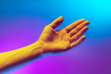 Obraz na płótnie Canvas Studio shot of aethentic human hand isolated on gradient purple-blue background in neon light. Concept of human relation, community, togetherness