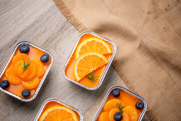 Fresh orange cake topping with orange and blueberry in foil cup.