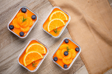 Fresh orange cake topping with orange and blueberry in foil cup.