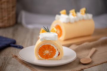 Orange roll cake topping with fresh cream orange and rosemary paste on white plate.