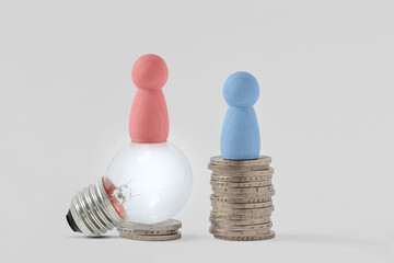 Pink pawns with light bulb and blue pawn on piles of coins - Concept of creativity and gender pay...