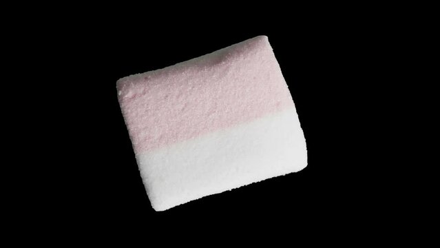 One close-up marshmallow rotates, isolated on a black background
