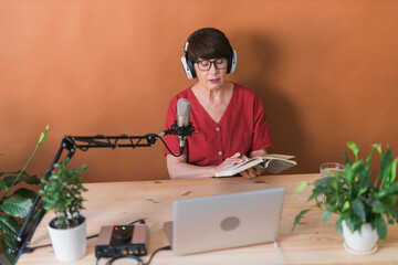 Middle-aged female radio presenter talking into the microphone and reading news - radio broadcast...