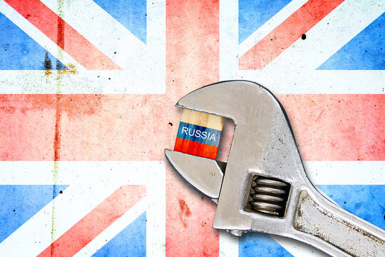 Flag of Russia on a wooden block, clamped with a wrench, against the background of the flag of England. Sanctions. Country isolation. Economic blockade. Economic. Politics.