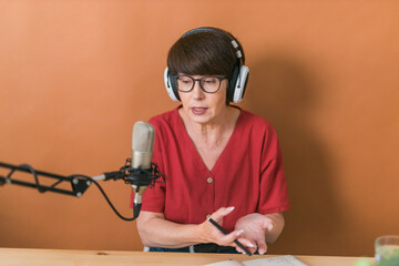 Middle-aged female radio presenter talking into the microphone and reading news - radio broadcast...