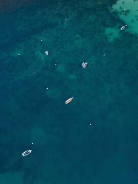 Aerial view of fishing boats and buoys seen from above over beautiful turquoise waters, Lulworth Cove, Dorset, United Kingdom.