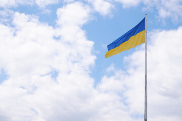 Flag of Ukraine on a high flagpole isolated on a blue sky background. Symbols of Ukraine. The concept of freedom of an independent free country.