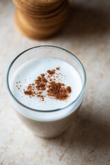Hot coffee with milk foam and cinnamon in a transparent glass.