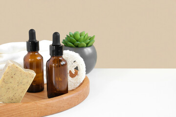 Glass bottles on wooden plate. Natural skin care SPA beauty product design. Mineral organic oil cosmetics on beige background. Earth tones. Mock-Up. Oily pipette. Face and body treatment. Front View