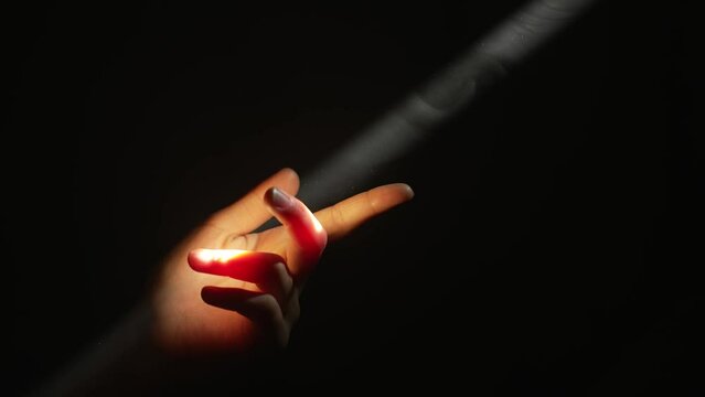 Woman's fingers touching a beam of light