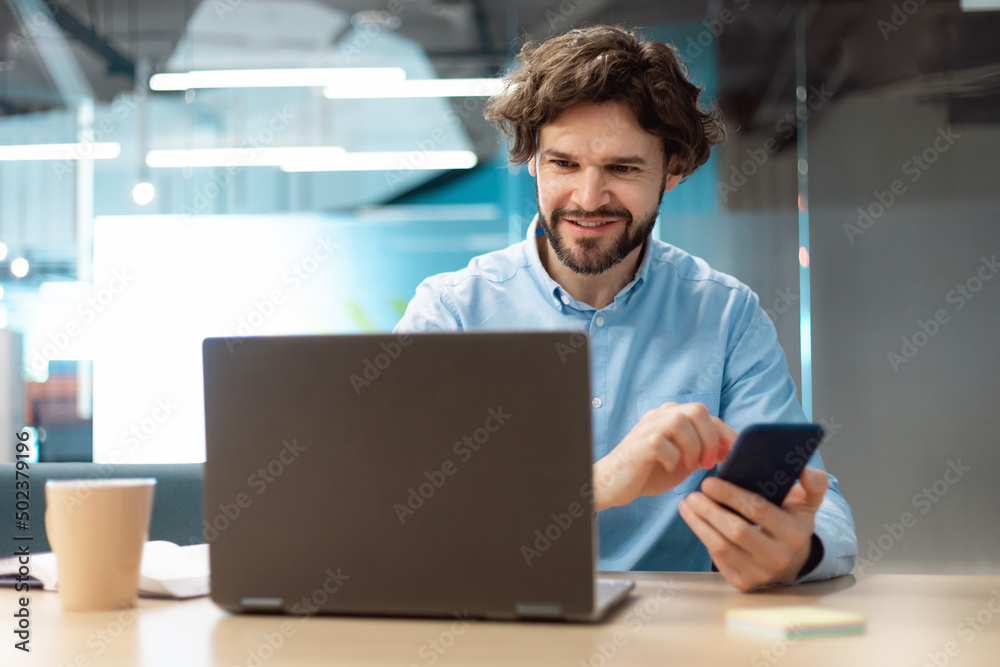 Aufkleber portrait of smiling man using smartphone and pc at office