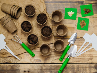 Top view of seeds and garden tools on a wooden background. Growing seedlings using peat cups.