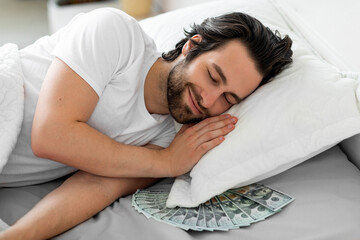 Smiling bearded guy sleeping with cash under his pillow