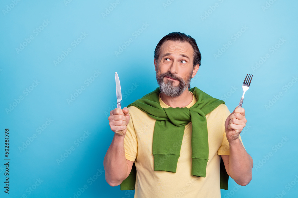 Sticker Photo of handsome minded man hold knife fork look interested empty space isolated on blue color background