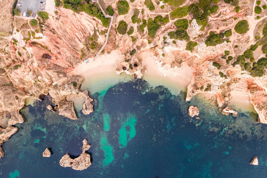 Aerial view of Praia do Camilo, a beautiful paradise beach along the coast with scenic cliffs near Ponta da Piedade, Lagos, Algarve region, Portugal.