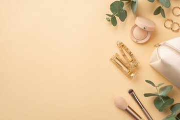 Top view photo of gold rings eyeshadow makeup brushes cosmetic bag barrettes and eucalyptus on isolated pastel beige background with copyspace