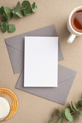 Workplace concept. Top view vertical photo of paper sheet two grey envelopes cup of tea candle on...