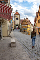 beautiful architecture of romantic Rothenburg ob der Tauber with timbered Fachwerkhaus syle houses in Bavaria Germany with a tourist woman walking