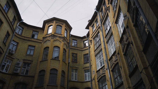Courtyard of old round building in city. Action. Bottom view of old house with courtyard well on background of sky. Old closed courtyards of houses in St. Petersburg