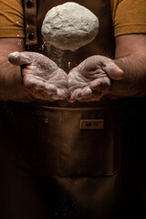 Hands of baker kneading dough isolated on black background. prepares ecologically natural pastries. vertical image. place for text