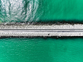 Areal view of a stone pier and road surrounded by water with beautiful color