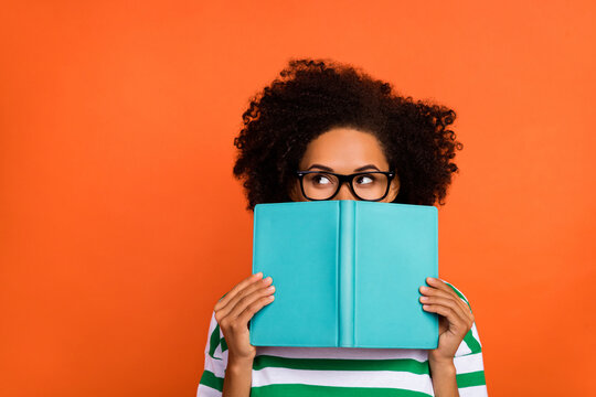 Portrait of attractive funny intellectual wavy-haired girl reading diary closing face copy space isolated on bright orange color background