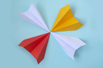 multicolored paper planes on a blue background. The concept of leadership, teamwork and courage.