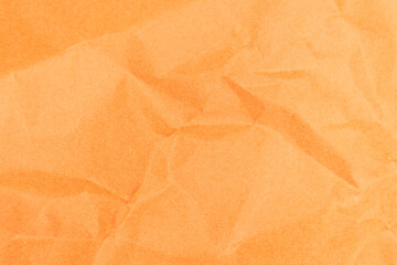 Crumpled orange color paper texture background. Close-up of sheet of paper.