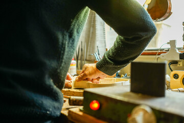 Closeup shot of a violin maker working with wood